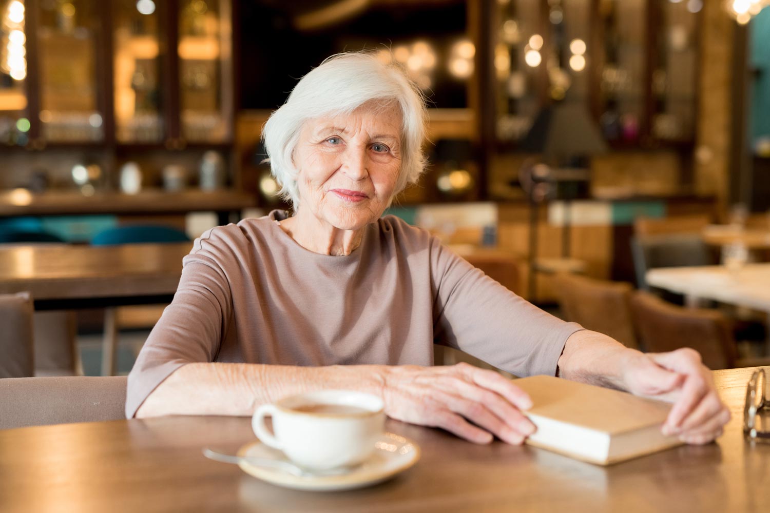 Senior Woman Smiling With Book And Coffee