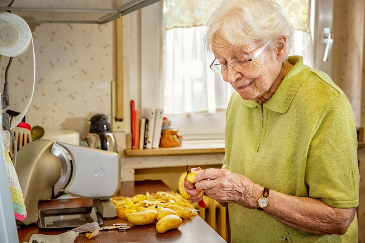 VRS Lakeside Gardens Senior peeling potatoes for cooking in assisted living suite